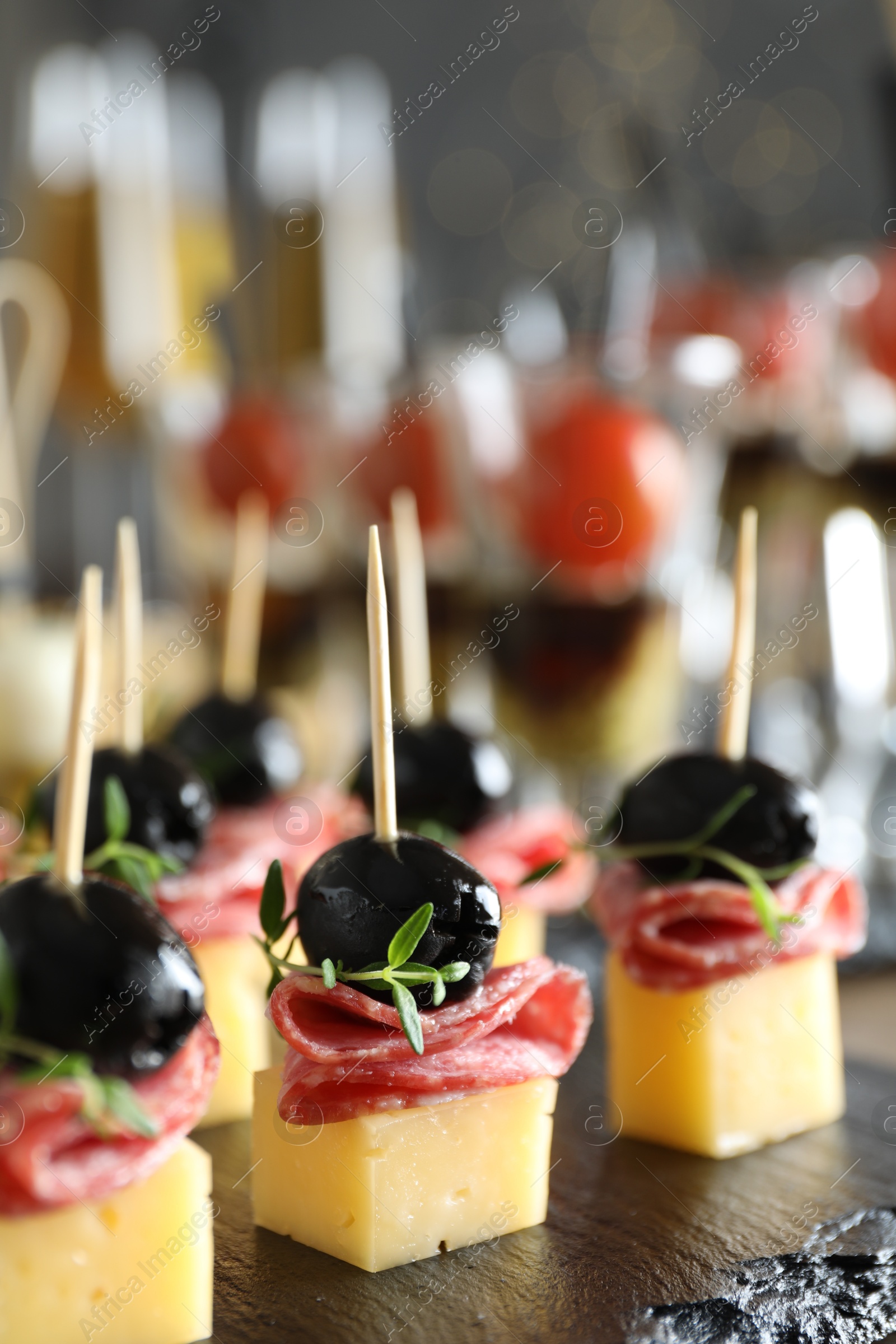 Photo of Tasty canapes with cheese, black olives and salami on table, closeup