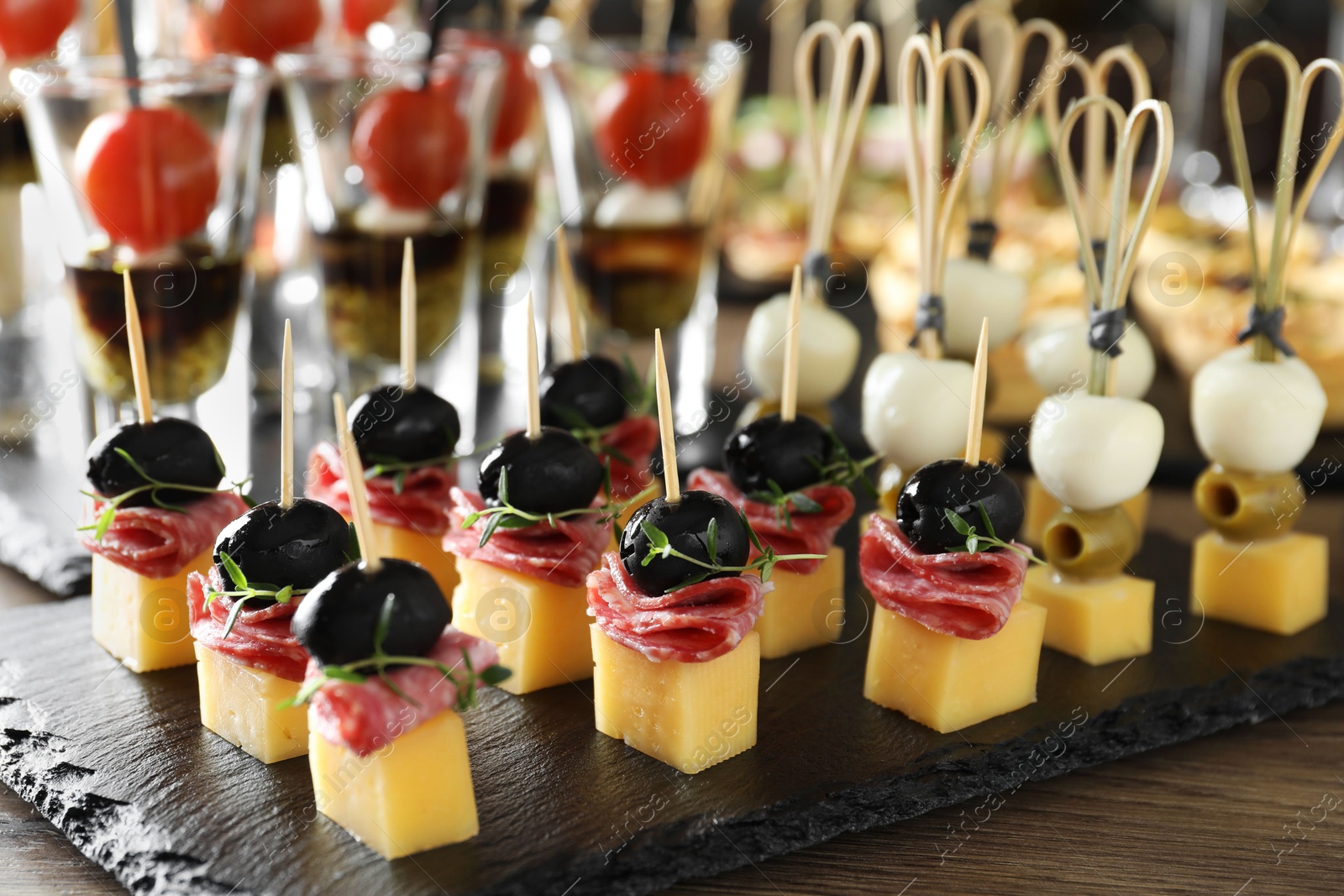 Photo of Many different tasty canapes on wooden table, closeup