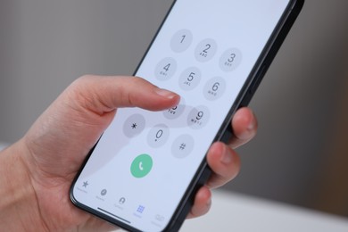 Photo of Woman dialing number on smartphone against blurred background, closeup