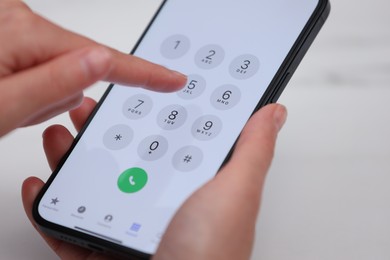 Photo of Woman dialing number on smartphone against blurred background, closeup