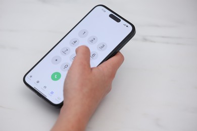 Photo of Woman dialing number on smartphone at white marble table, closeup