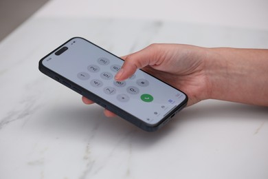 Photo of Woman dialing number on smartphone at white marble table, closeup