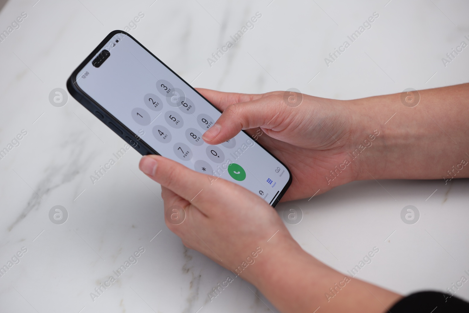 Photo of Woman dialing number on smartphone at white marble table, closeup