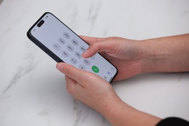 Photo of Woman dialing number on smartphone at white marble table, closeup