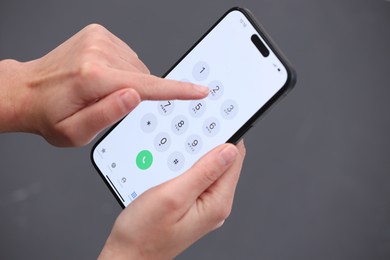 Photo of Woman dialing number on smartphone against blurred grey background, closeup