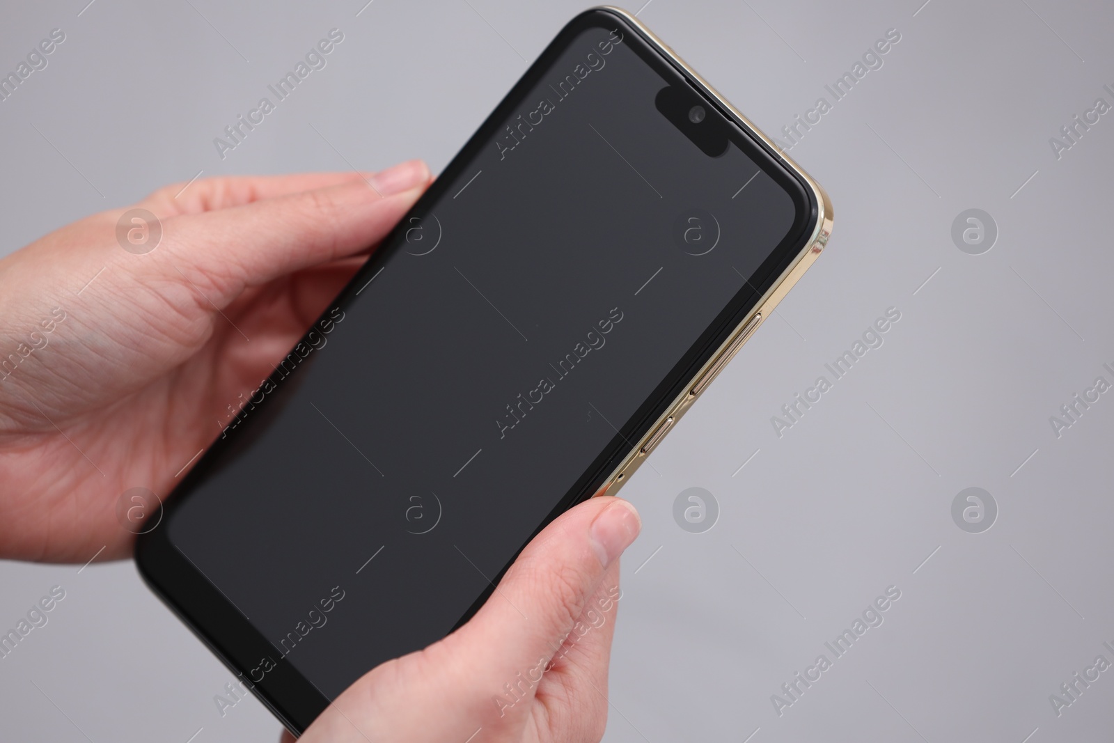 Photo of Woman holding smartphone with blank screen on grey background, closeup