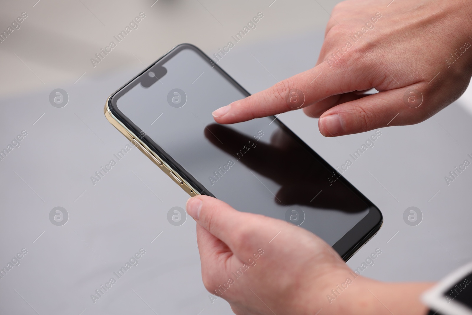 Photo of Woman using smartphone with blank screen on grey background, closeup