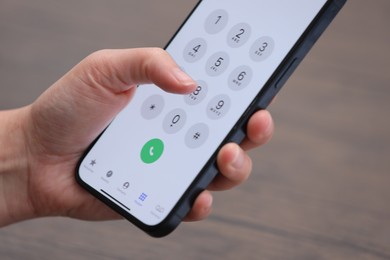 Photo of Woman dialing number on smartphone against blurred background, closeup