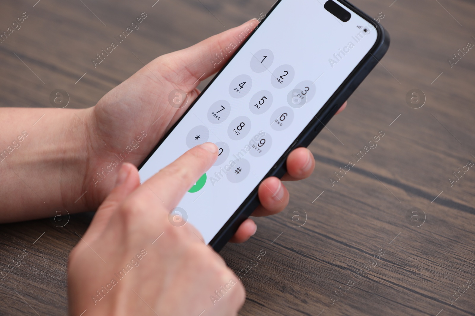 Photo of Woman dialing number on smartphone at wooden table, closeup