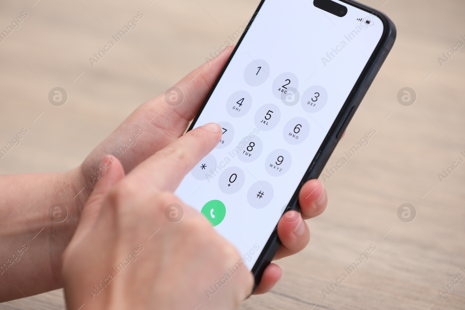 Photo of Woman dialing number on smartphone at wooden table, closeup