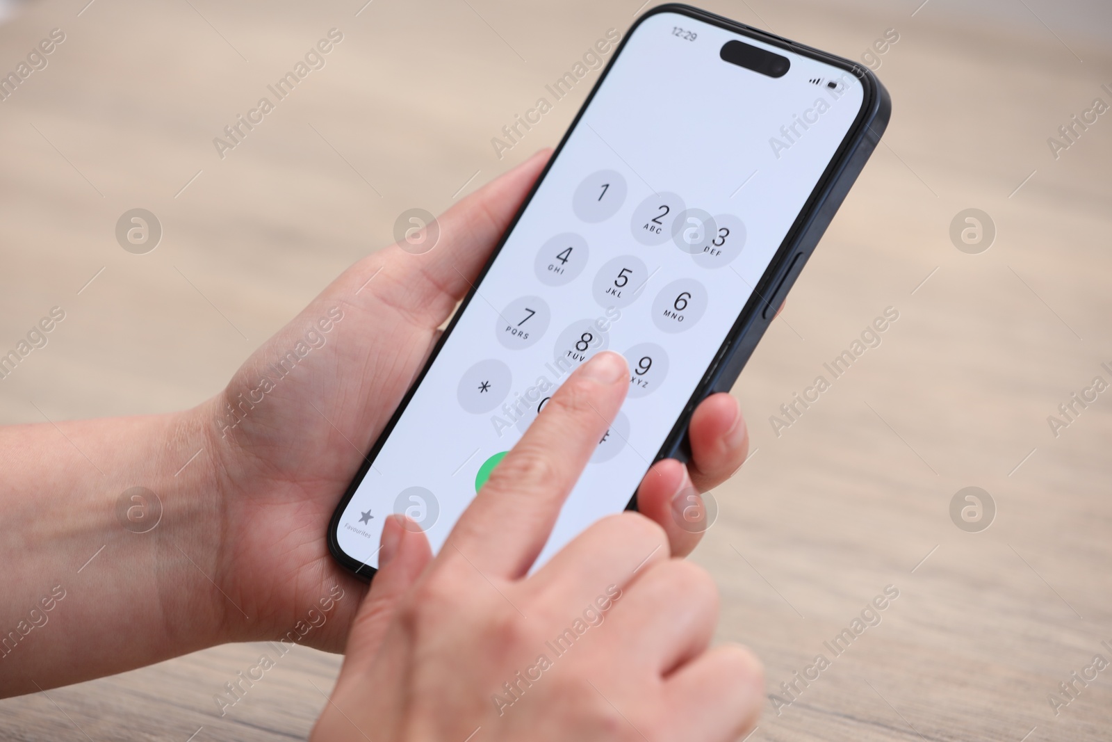 Photo of Woman dialing number on smartphone at wooden table, closeup