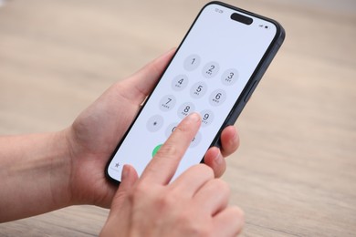 Photo of Woman dialing number on smartphone at wooden table, closeup