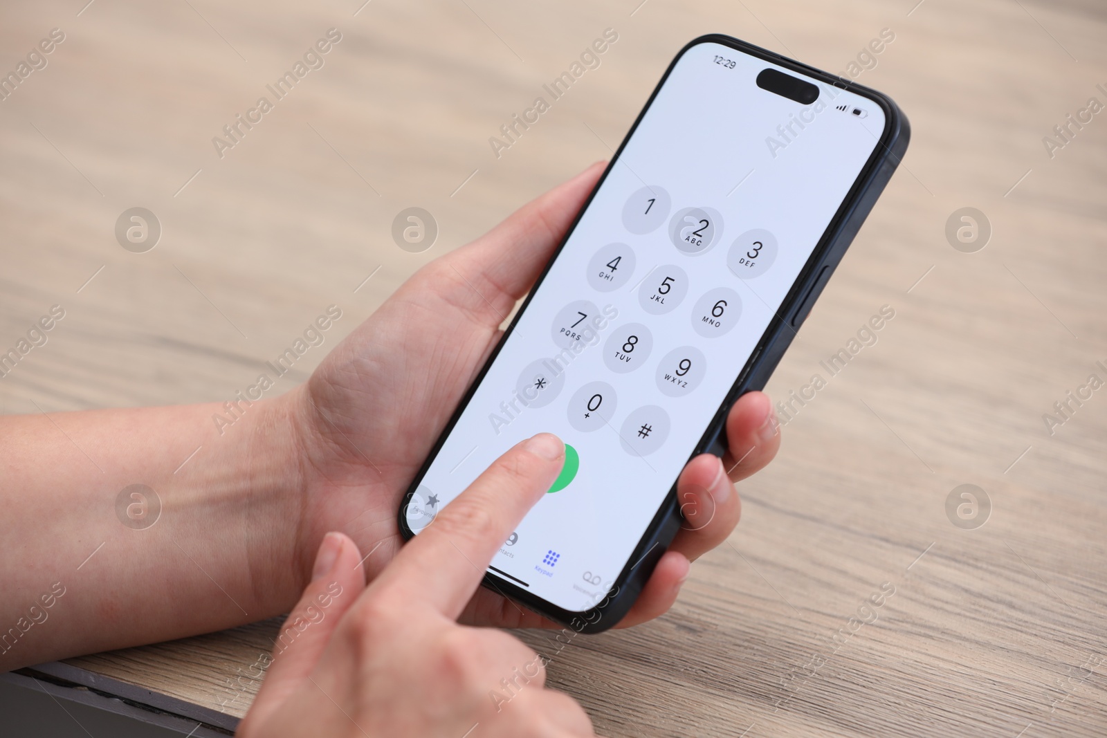 Photo of Woman dialing number on smartphone at wooden table, closeup