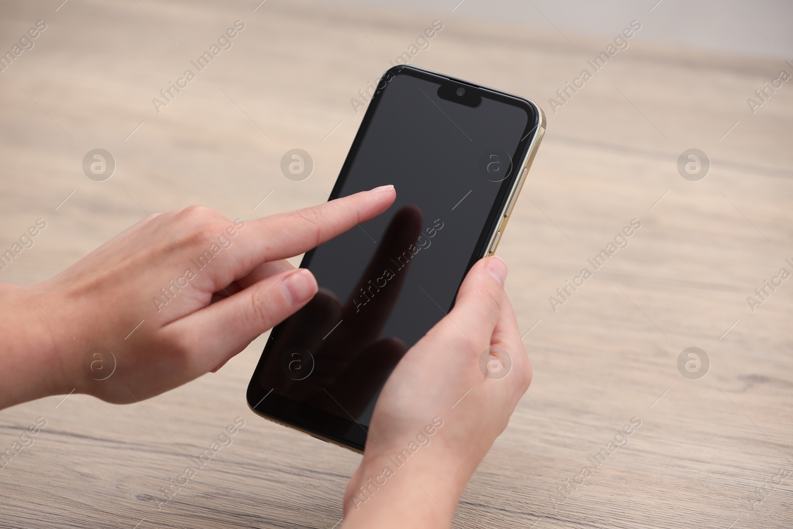 Photo of Woman using smartphone with blank screen at wooden table, closeup