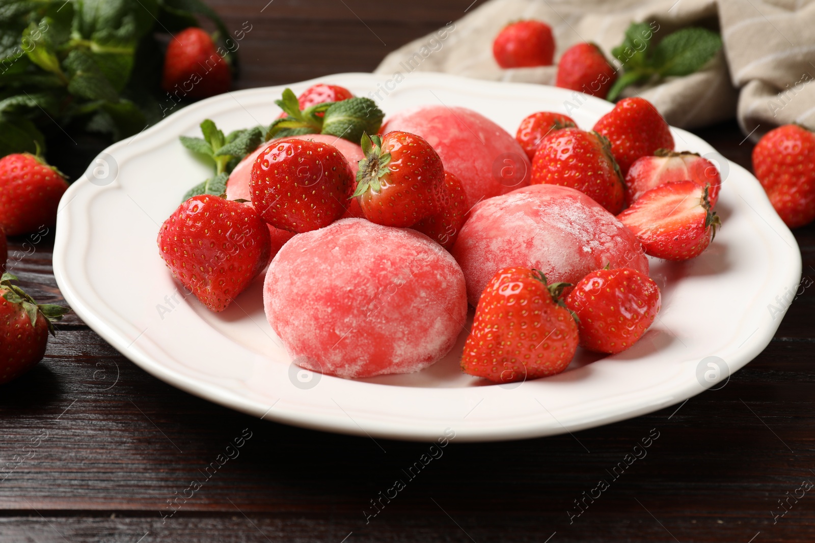 Photo of Delicious mochi, strawberries and mint on wooden table, closeup