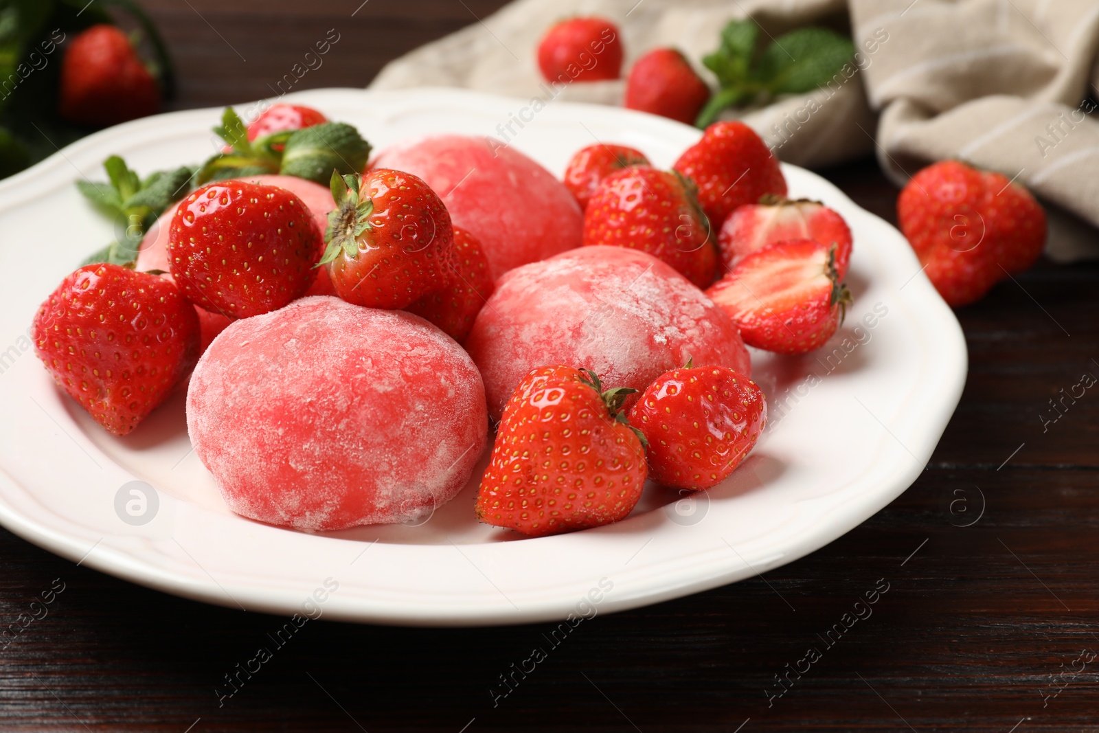 Photo of Delicious mochi, strawberries and mint on wooden table, closeup