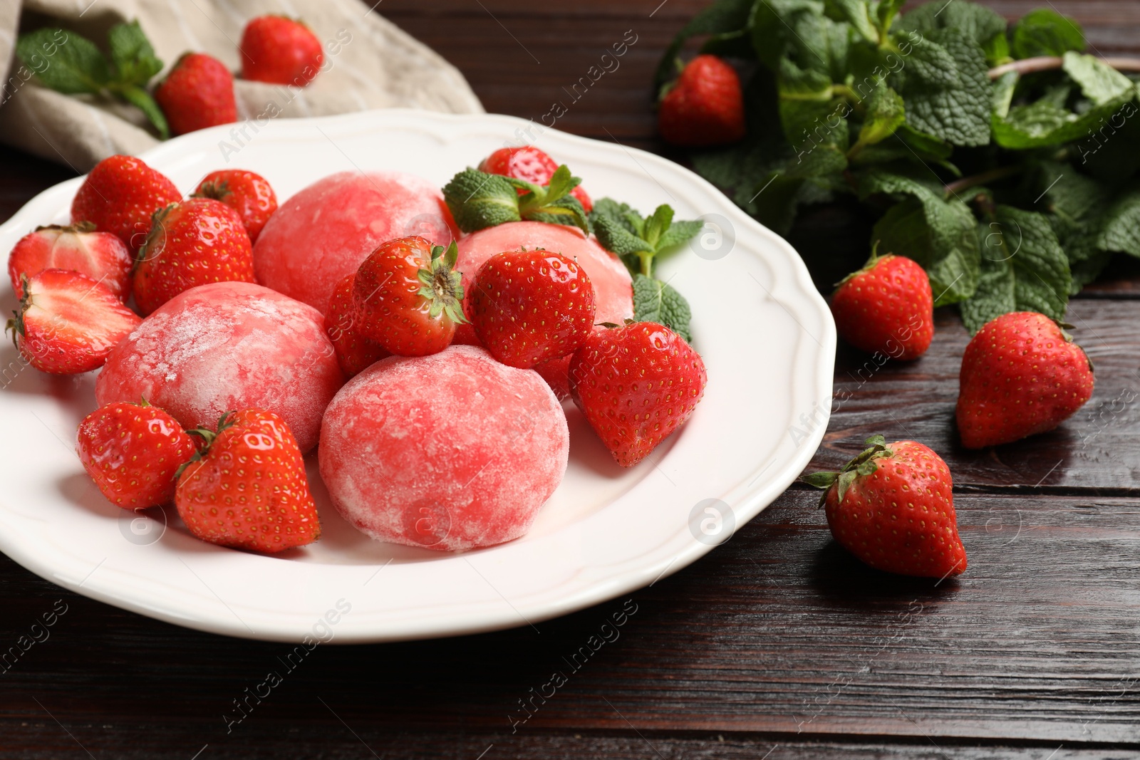 Photo of Delicious mochi, strawberries and mint on wooden table, closeup