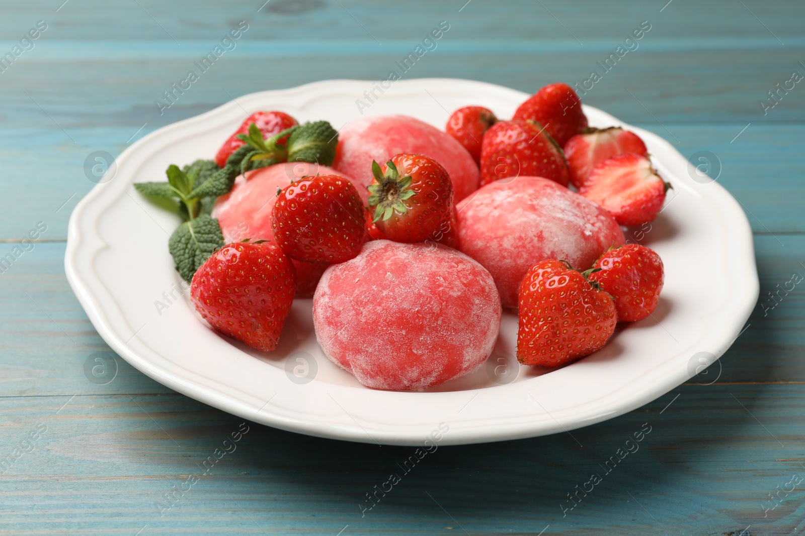 Photo of Delicious mochi, strawberries and mint on light blue wooden table, closeup