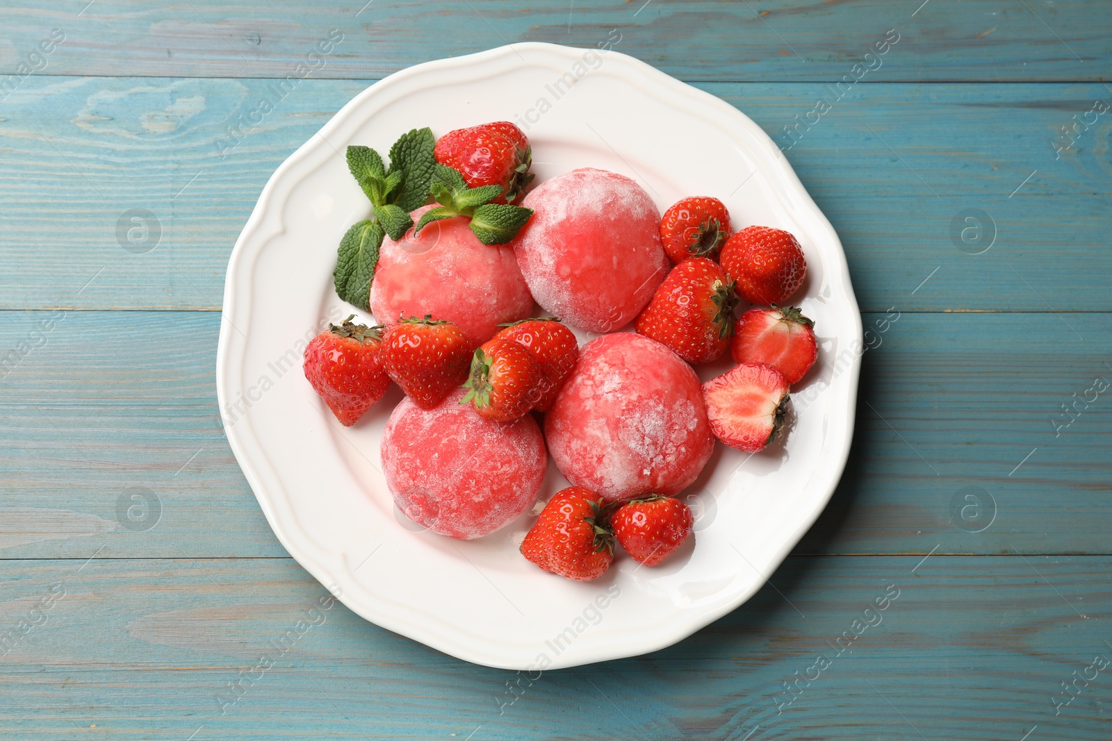 Photo of Delicious mochi, strawberries and mint on light blue wooden table, top view