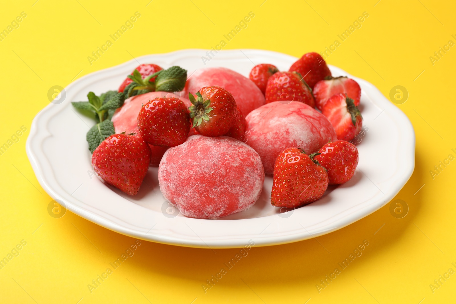 Photo of Delicious mochi, strawberries and mint on yellow background, closeup