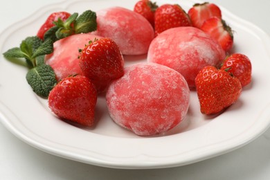 Photo of Delicious mochi, strawberries and mint on white table, closeup