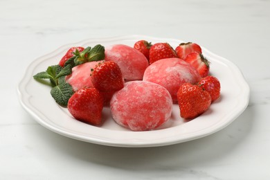 Photo of Delicious mochi, strawberries and mint on white marble table, closeup