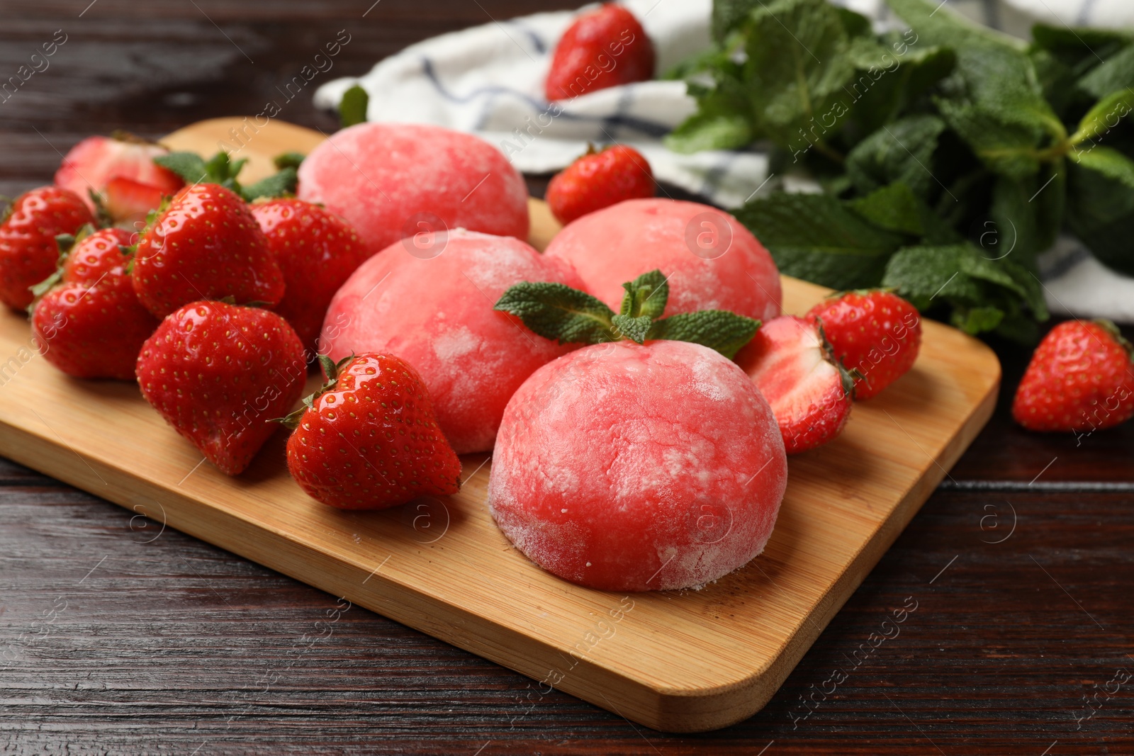 Photo of Delicious mochi, strawberries and mint on wooden table, closeup