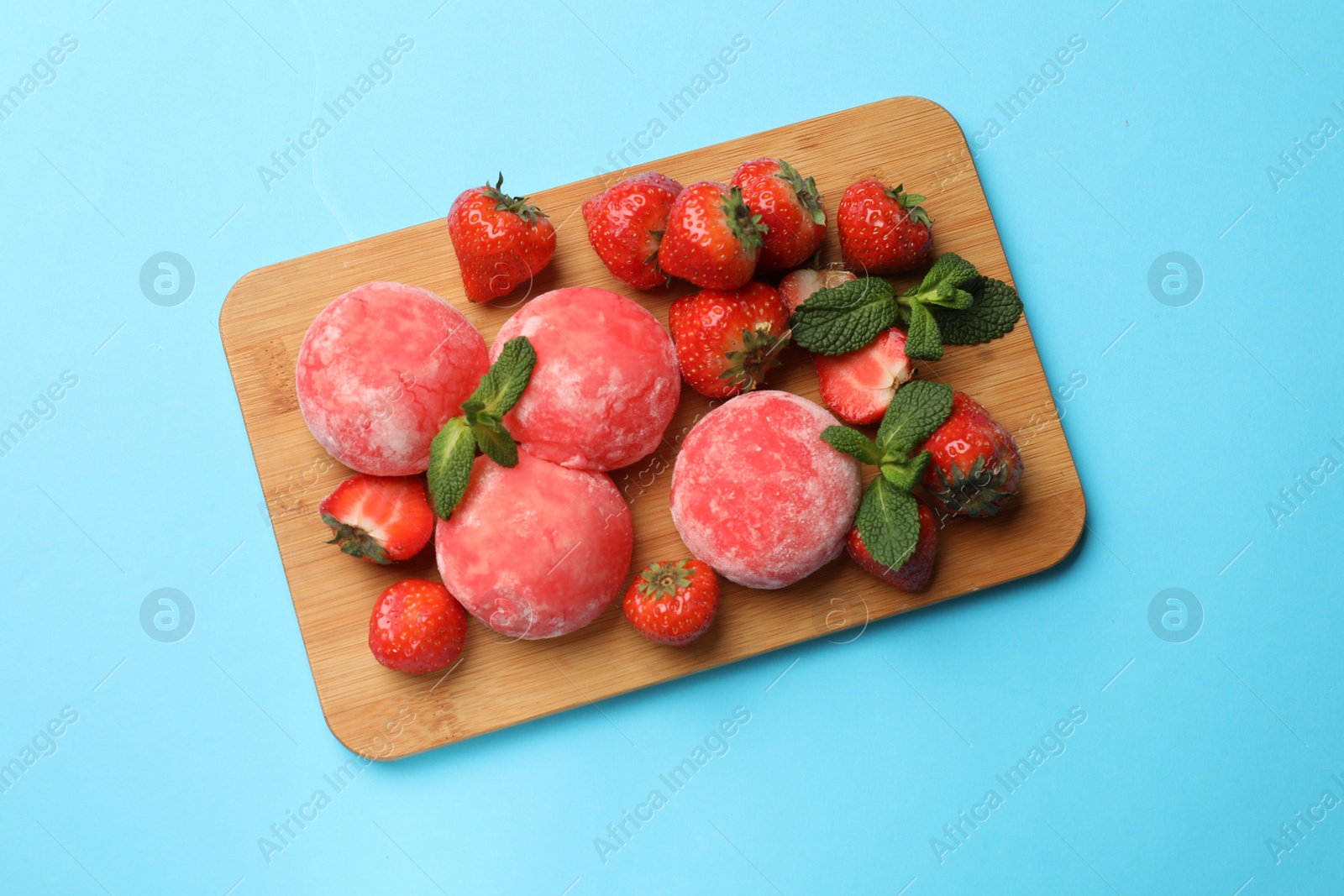 Photo of Delicious mochi, strawberries and mint on light blue background, top view