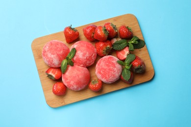 Photo of Delicious mochi, strawberries and mint on light blue background, top view