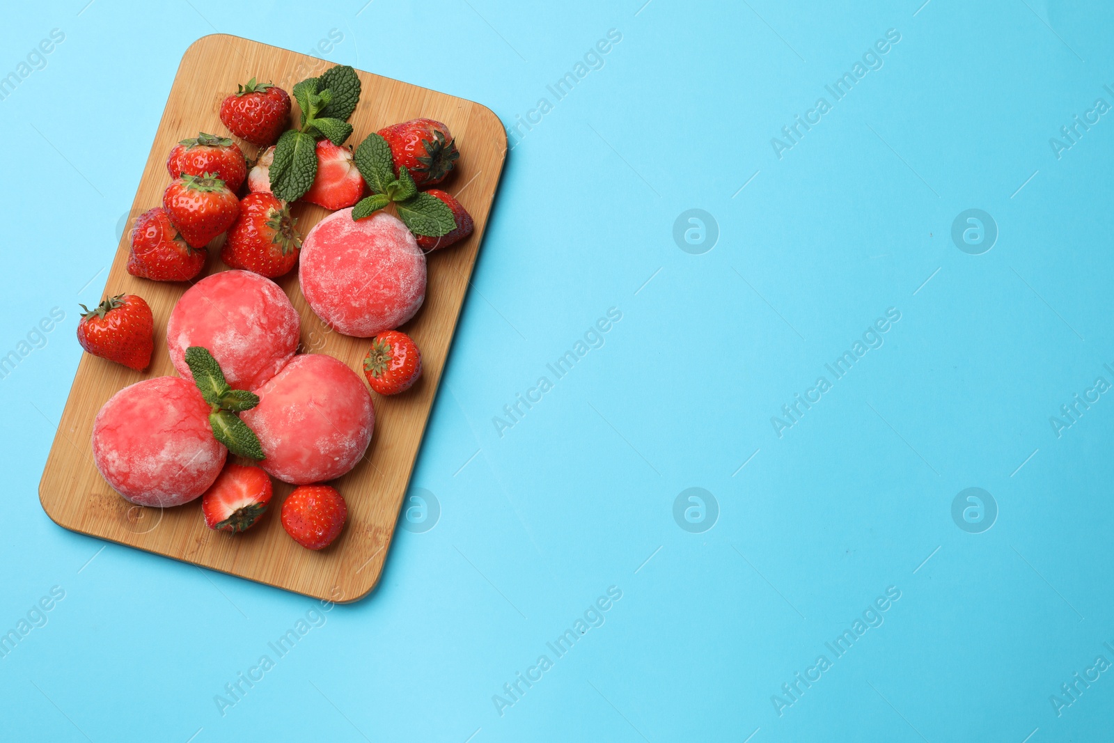 Photo of Delicious mochi, strawberries and mint on light blue background, top view. Space for text