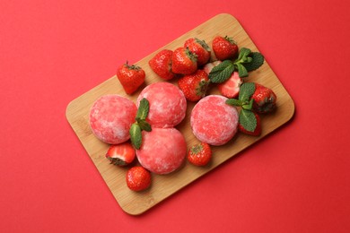 Photo of Delicious mochi, strawberries and mint on red background, top view