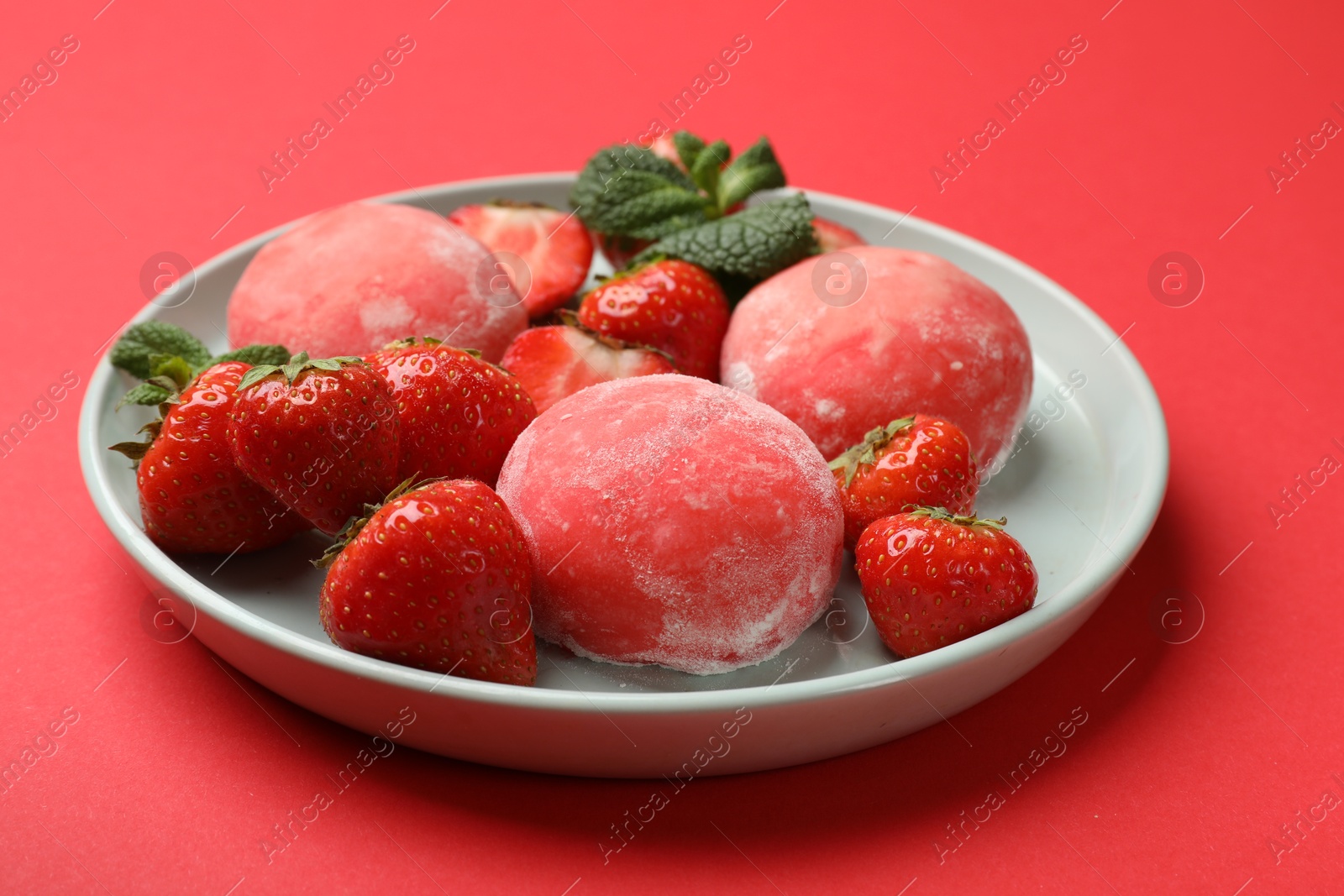 Photo of Delicious mochi, strawberries and mint on red background, closeup