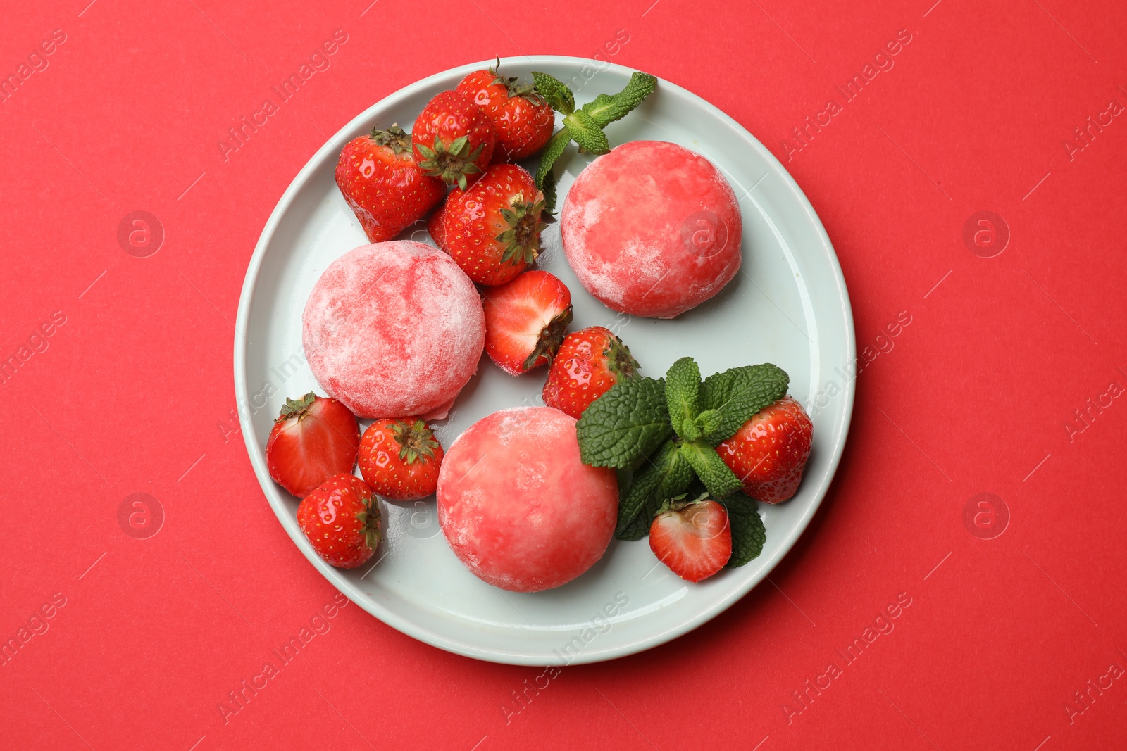 Photo of Delicious mochi, strawberries and mint on red background, top view