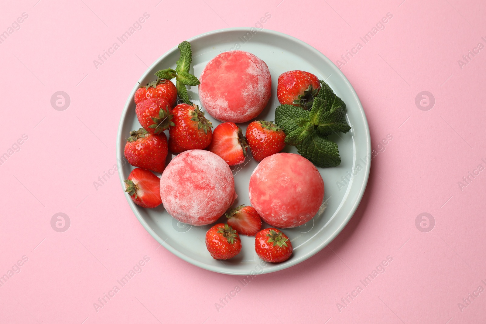 Photo of Delicious mochi, strawberries and mint on pink background, top view