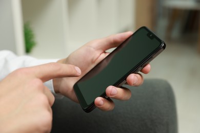 Photo of Man using smartphone with blank screen indoors, closeup