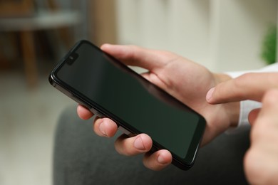 Photo of Man using smartphone with blank screen indoors, closeup