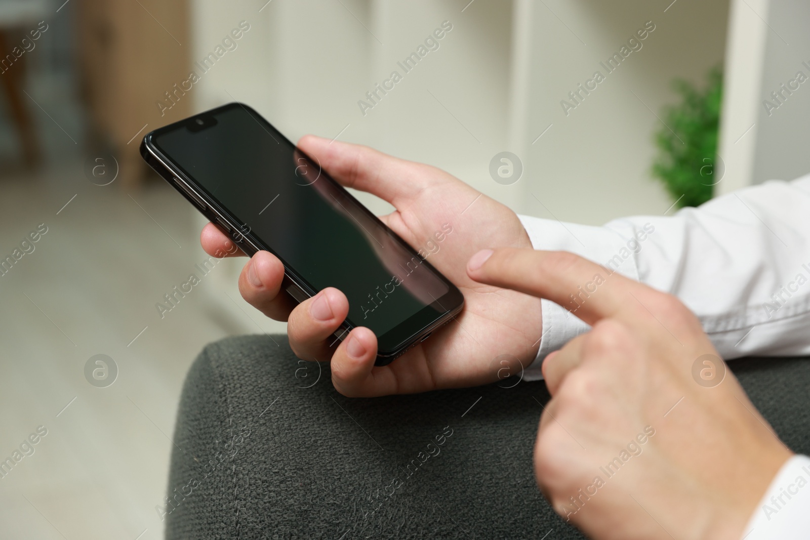 Photo of Man using smartphone with blank screen indoors, closeup