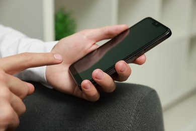 Photo of Man using smartphone with blank screen indoors, closeup