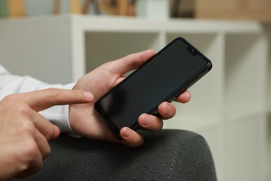 Photo of Man using smartphone with blank screen indoors, closeup