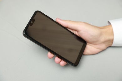 Photo of Man using smartphone with blank screen on grey background, closeup