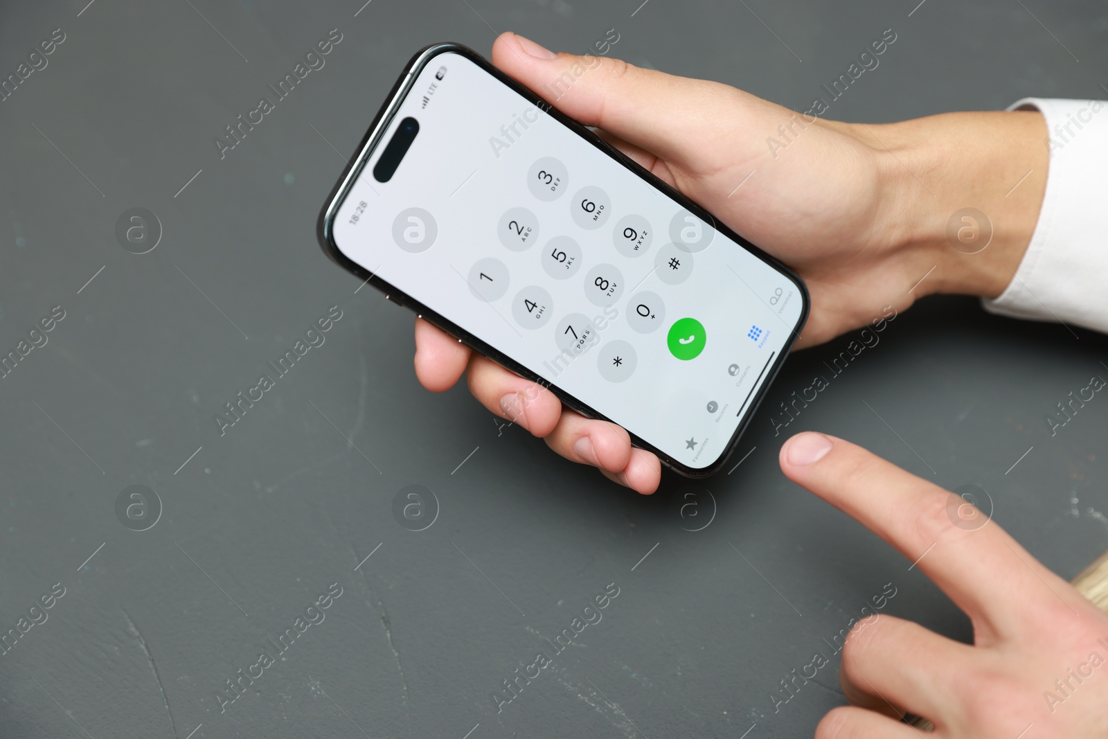 Photo of Man dialing number on smartphone at grey table, closeup. Space for text