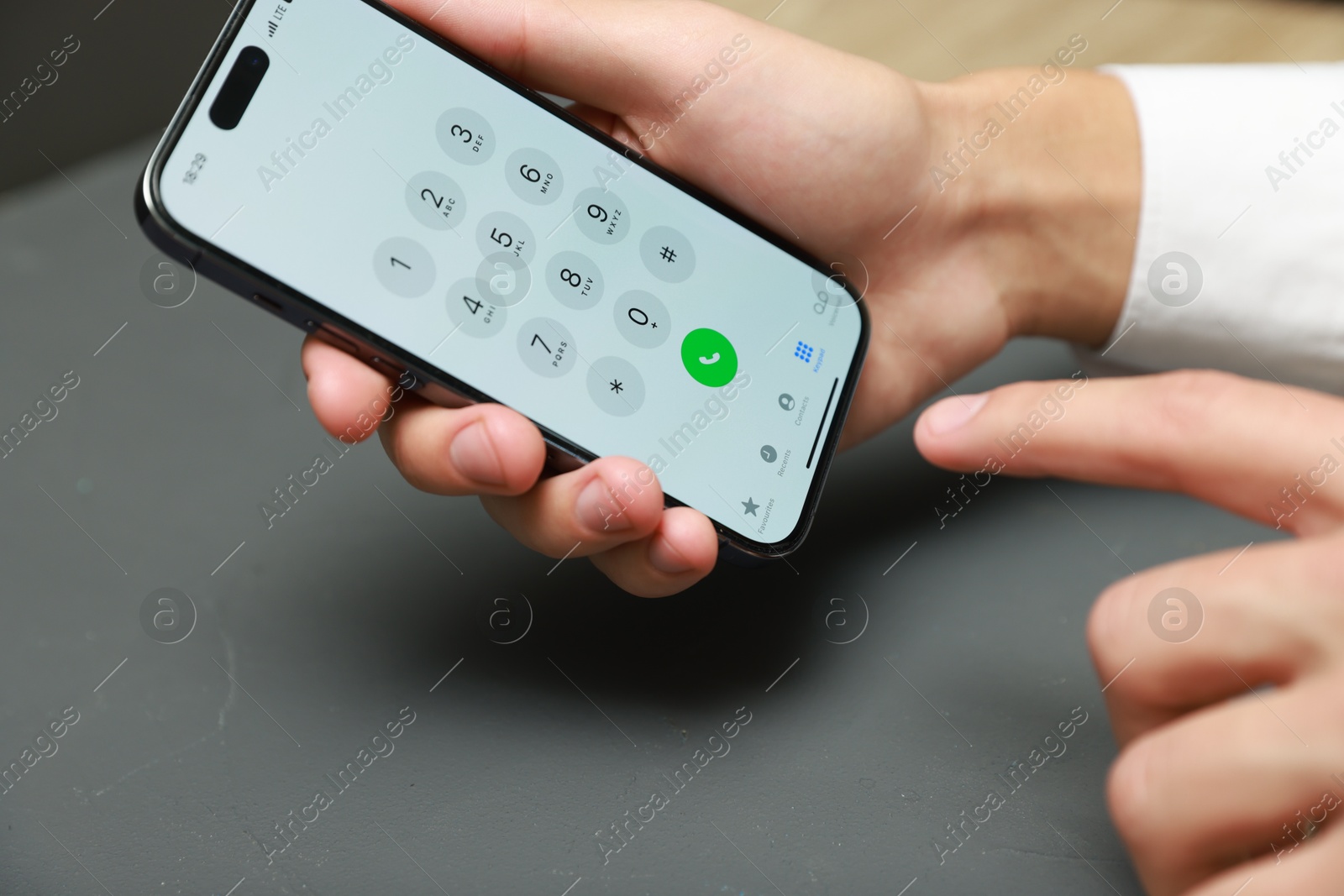 Photo of Man dialing number on smartphone at grey table, closeup