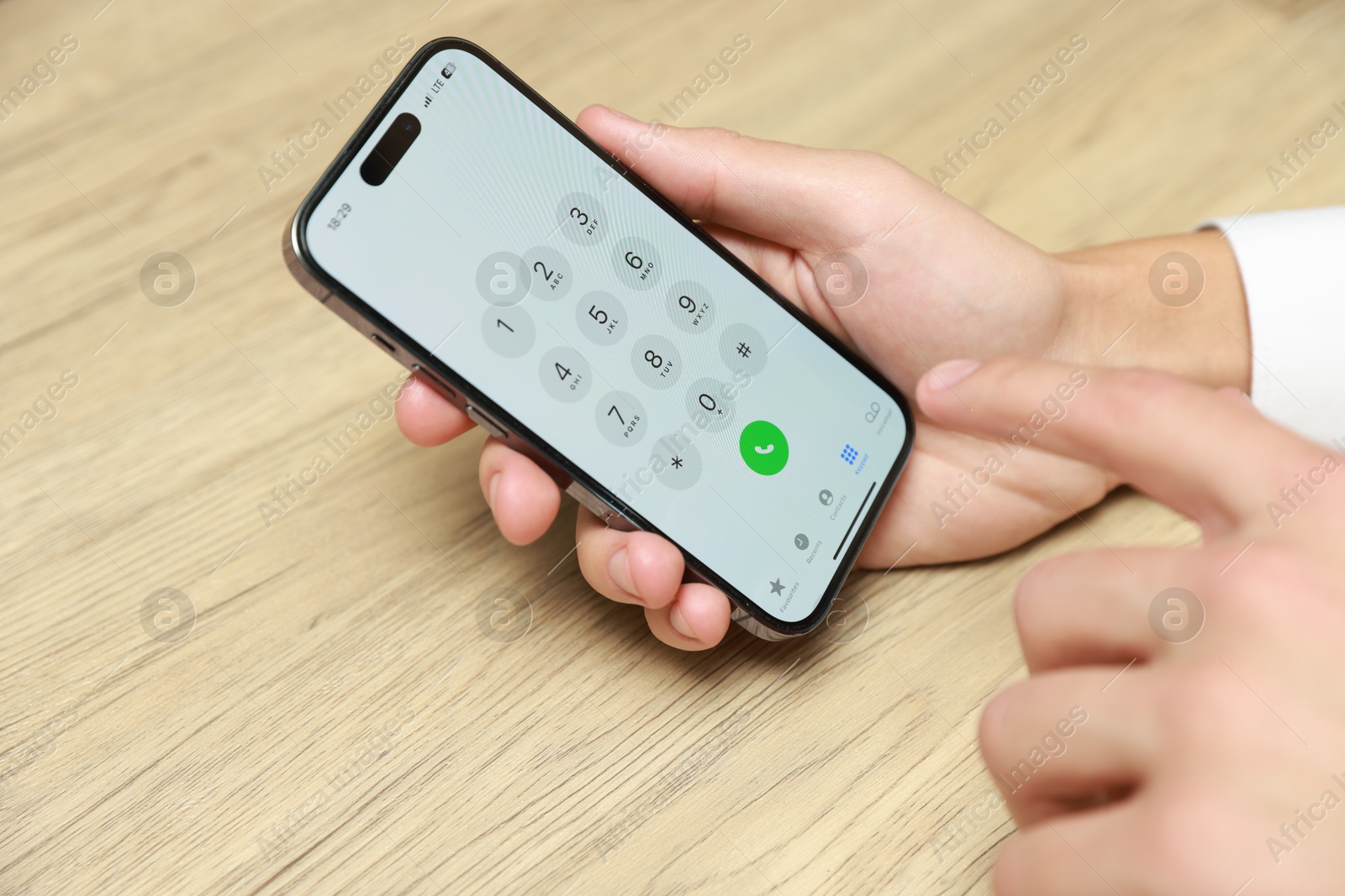 Photo of Man dialing number on smartphone at wooden table, closeup