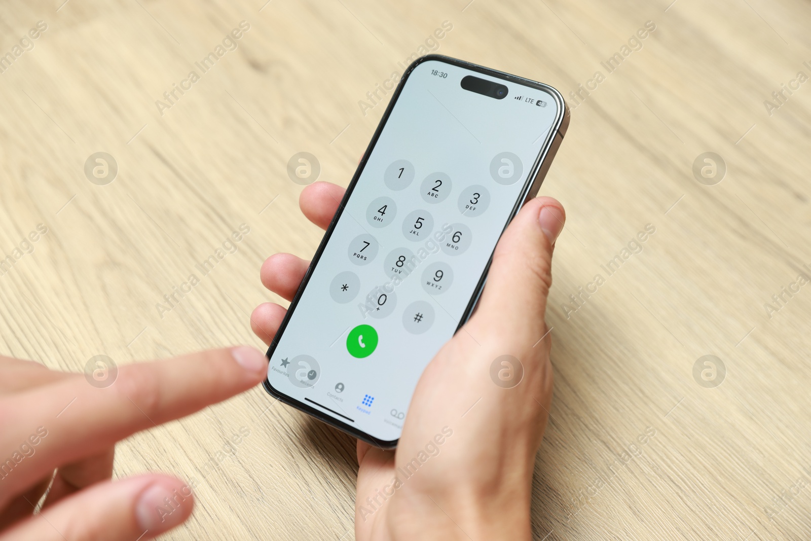 Photo of Man dialing number on smartphone at wooden table, closeup