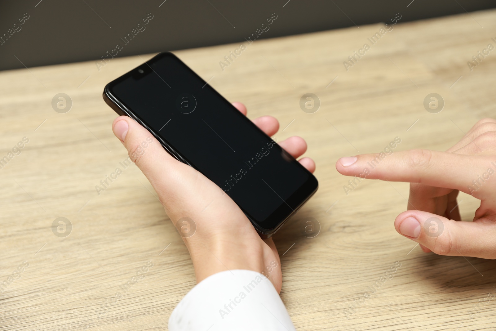 Photo of Man using smartphone with blank screen at wooden table, closeup