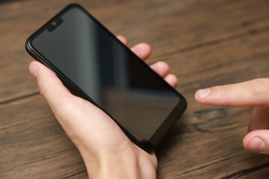 Photo of Man using smartphone with blank screen at wooden table, closeup