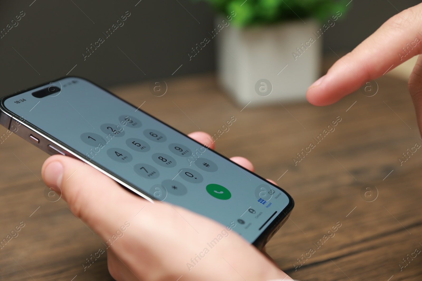 Photo of Man dialing number on smartphone at wooden table, closeup