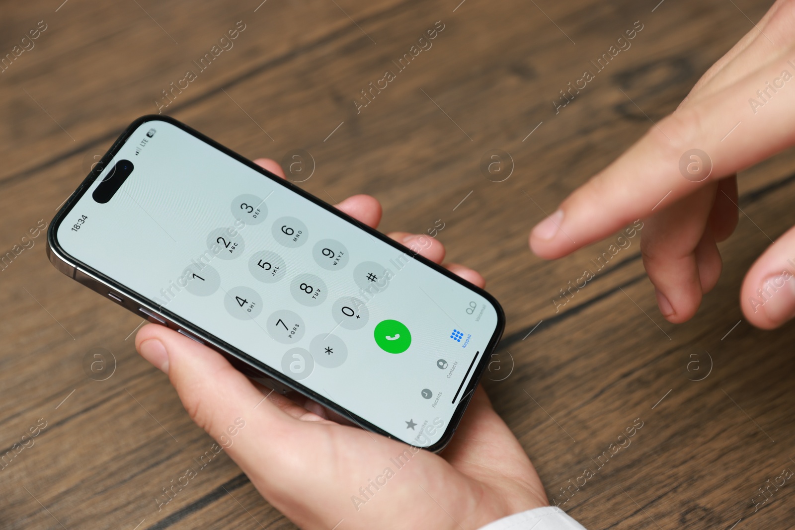 Photo of Man dialing number on smartphone at wooden table, closeup