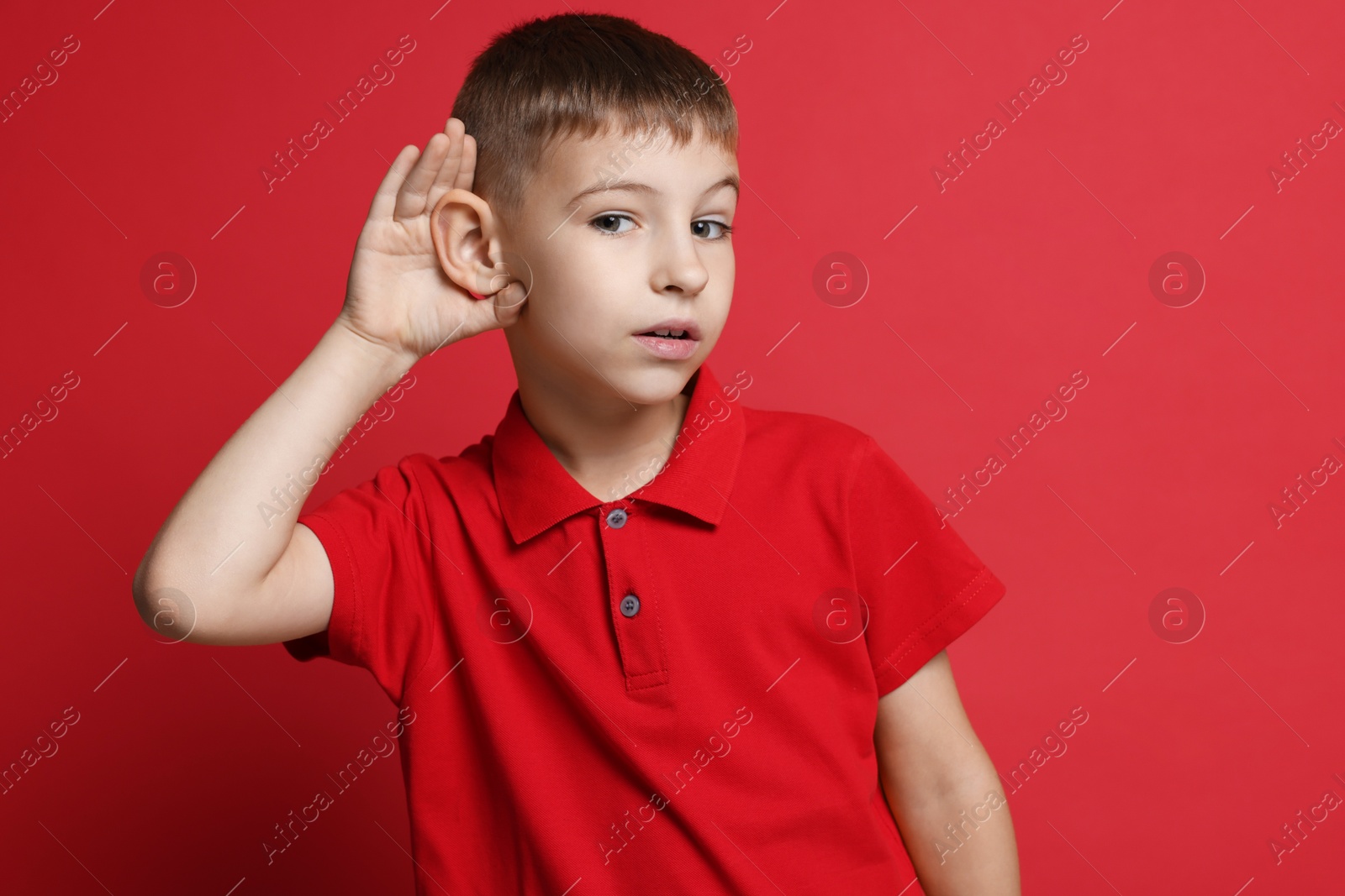 Photo of Little boy showing hand to ear gesture on red background