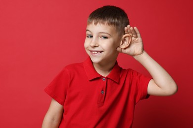 Photo of Little boy showing hand to ear gesture on red background